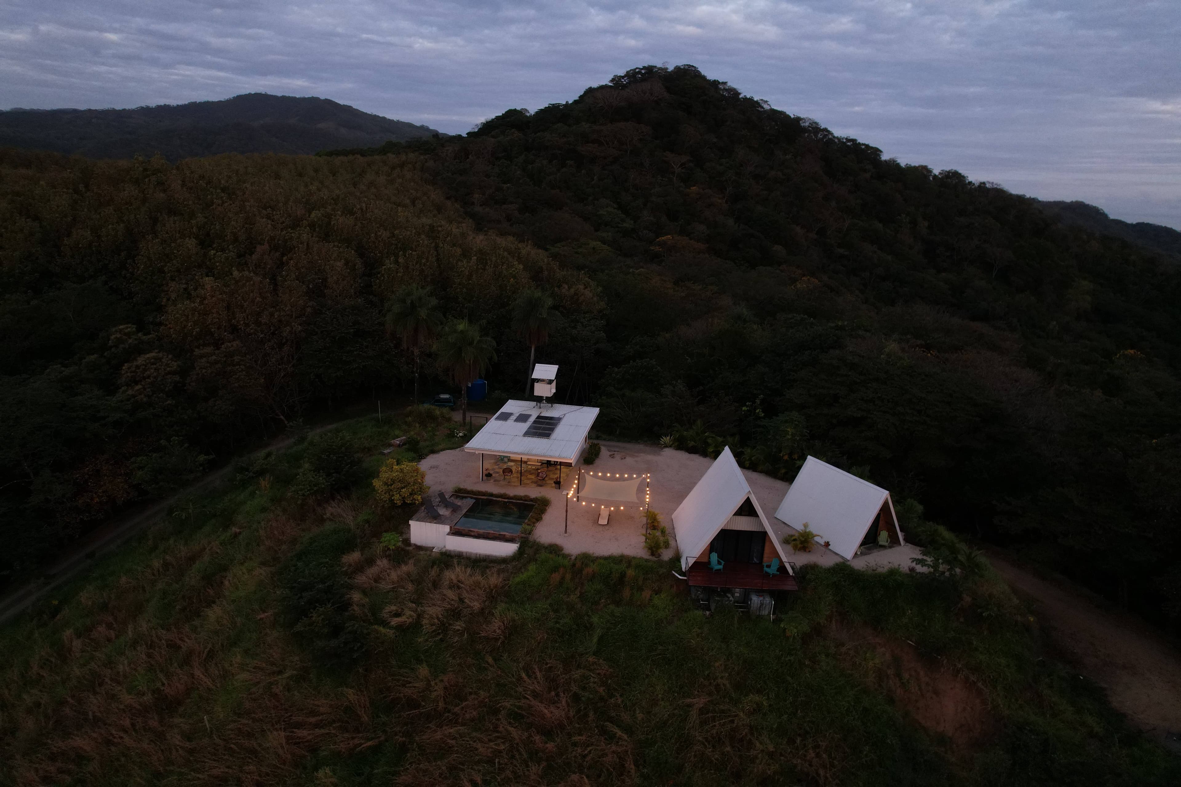 Night illuminated A-frame structures luxury vacation rental Costa Rica mountain retreat Blue Zone