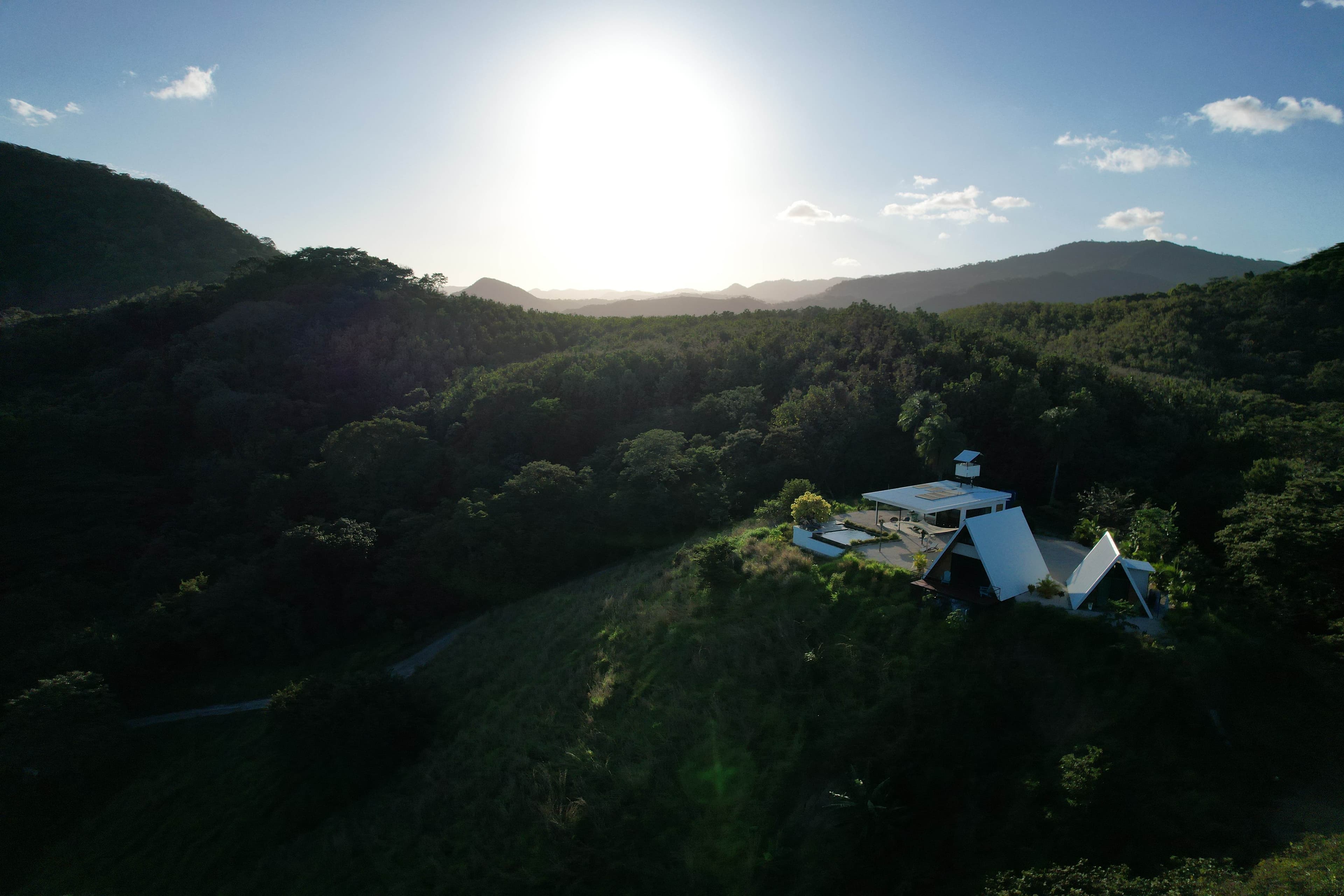 Aerial view of the sustainable farm and lodge on a green mountain in the Nicoya Blue Zone