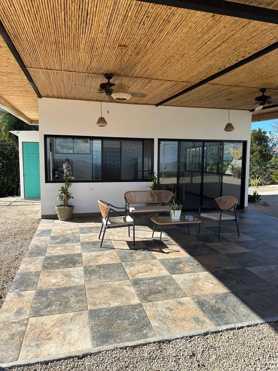Covered terrace with modern furniture, bamboo roof, and large windows, ideal for an upscale vacation stay