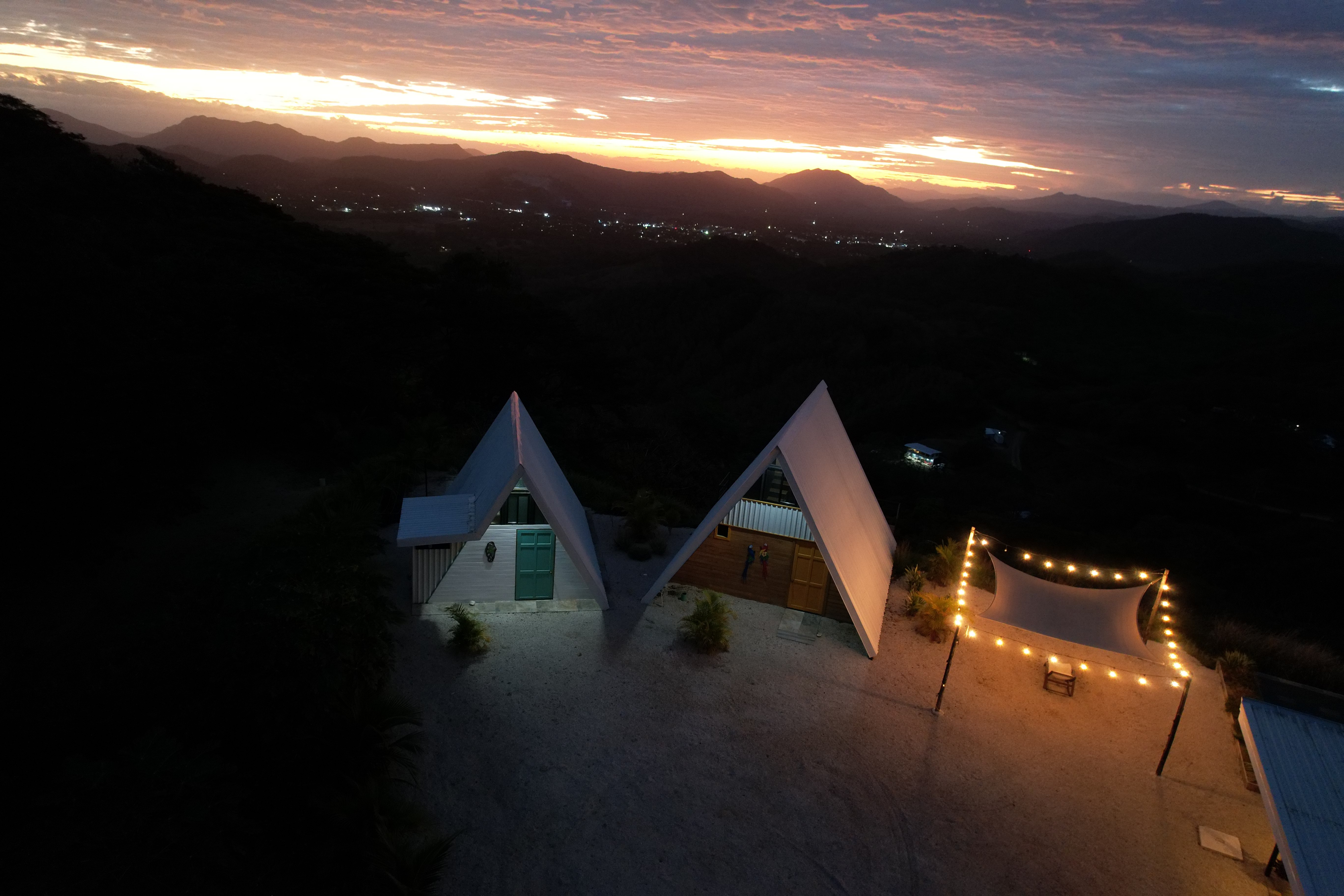 Sunrise aerial view of A-frame structures and infinity pool at an upscale Costa Rica vacation stay