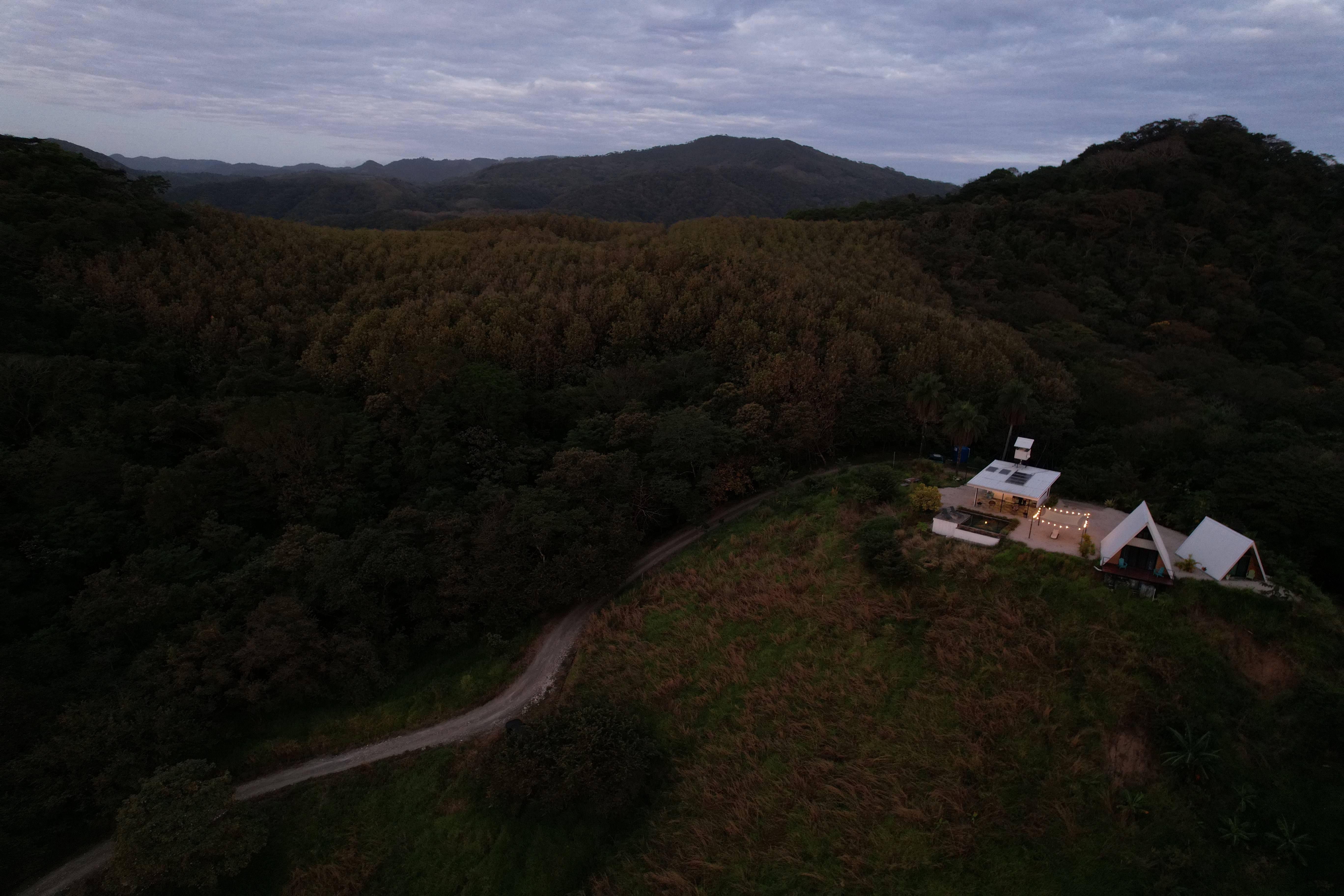 Night aerial view of the illuminated lodge against the vast Blue Zone mountainous landscape