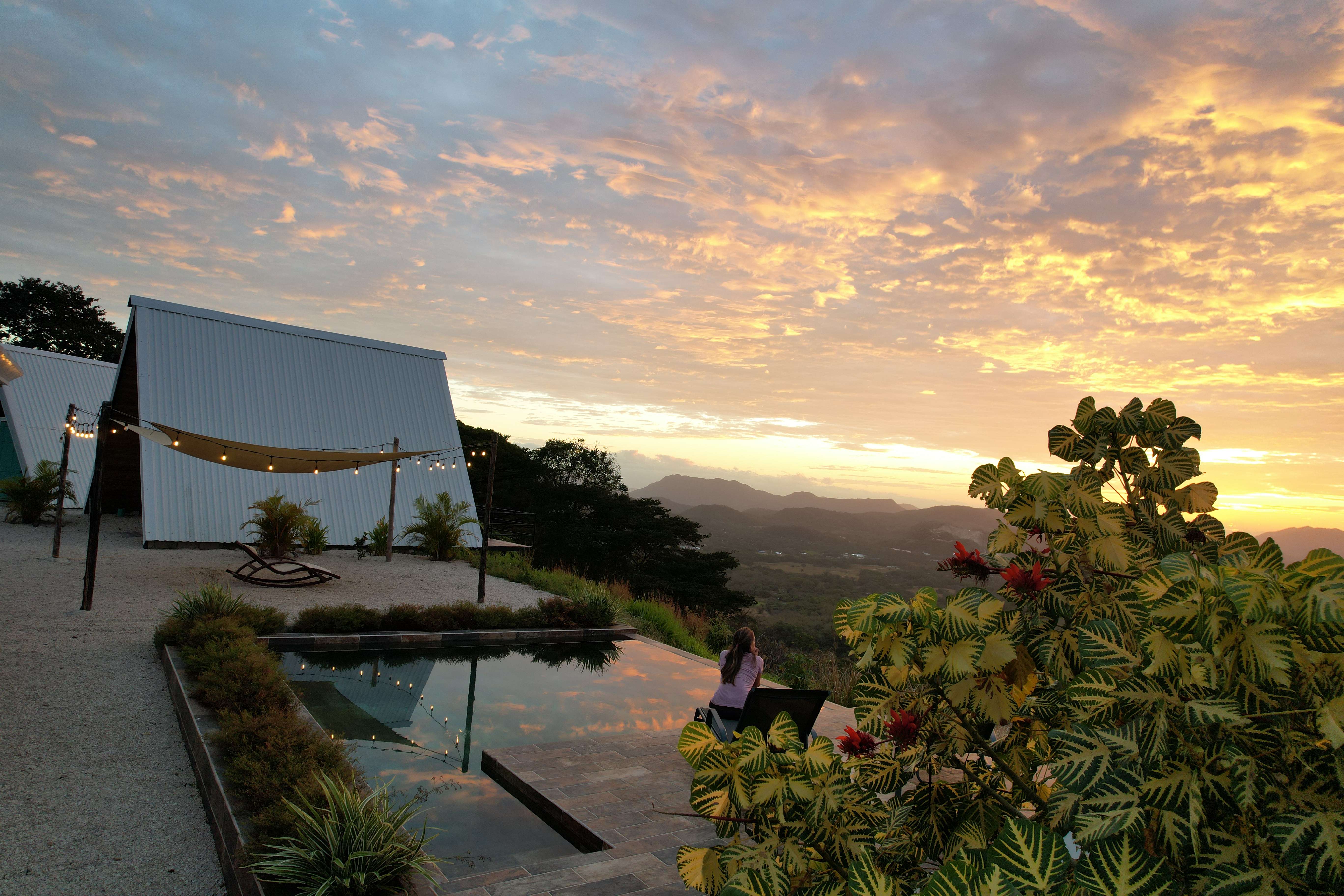 Infinity pool at sunrise with tropical plants and mountain view, part of your exclusive stay
