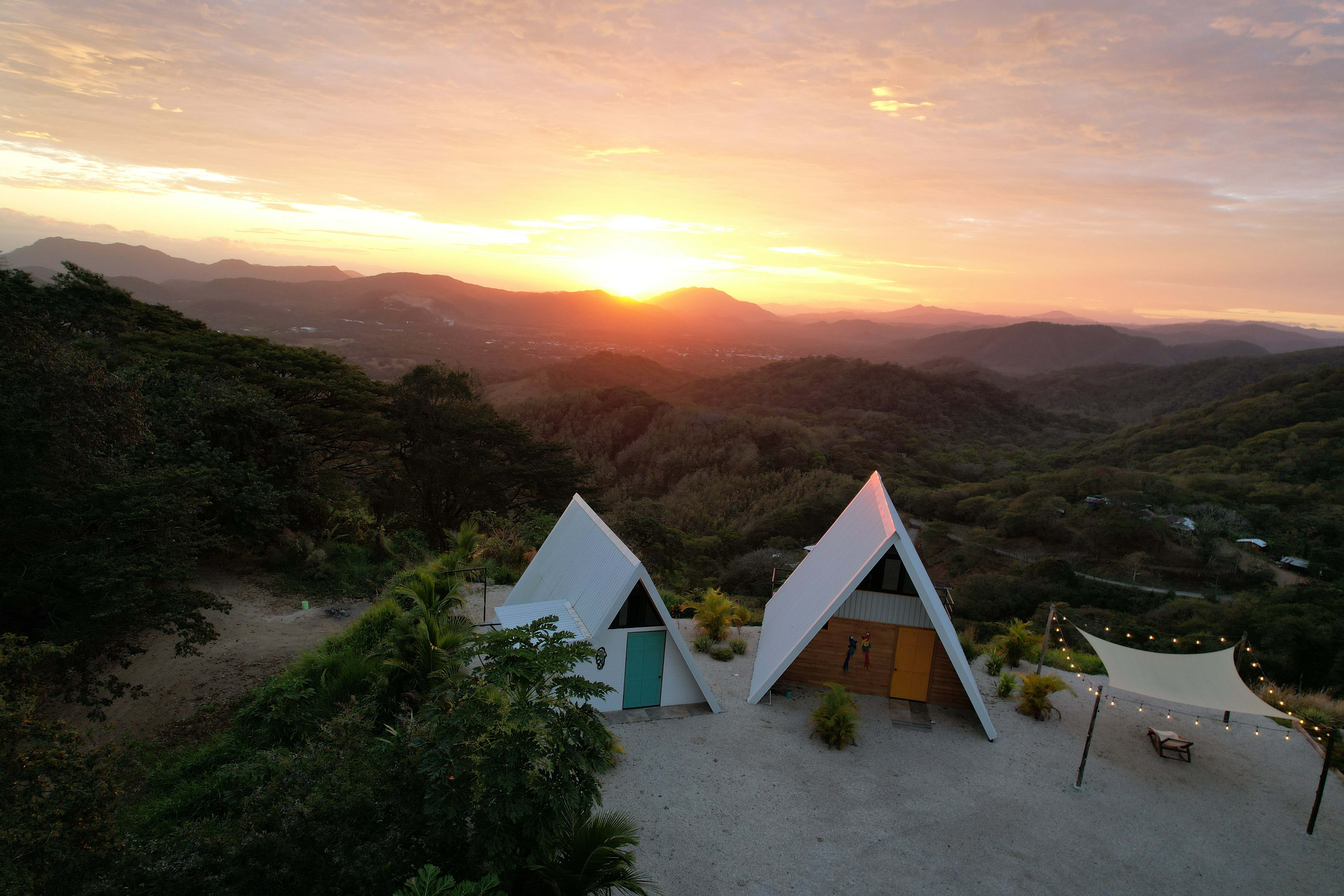 Sunrise aerial view of A-frame structures and spectacular golden sky at Bluesky Lodge